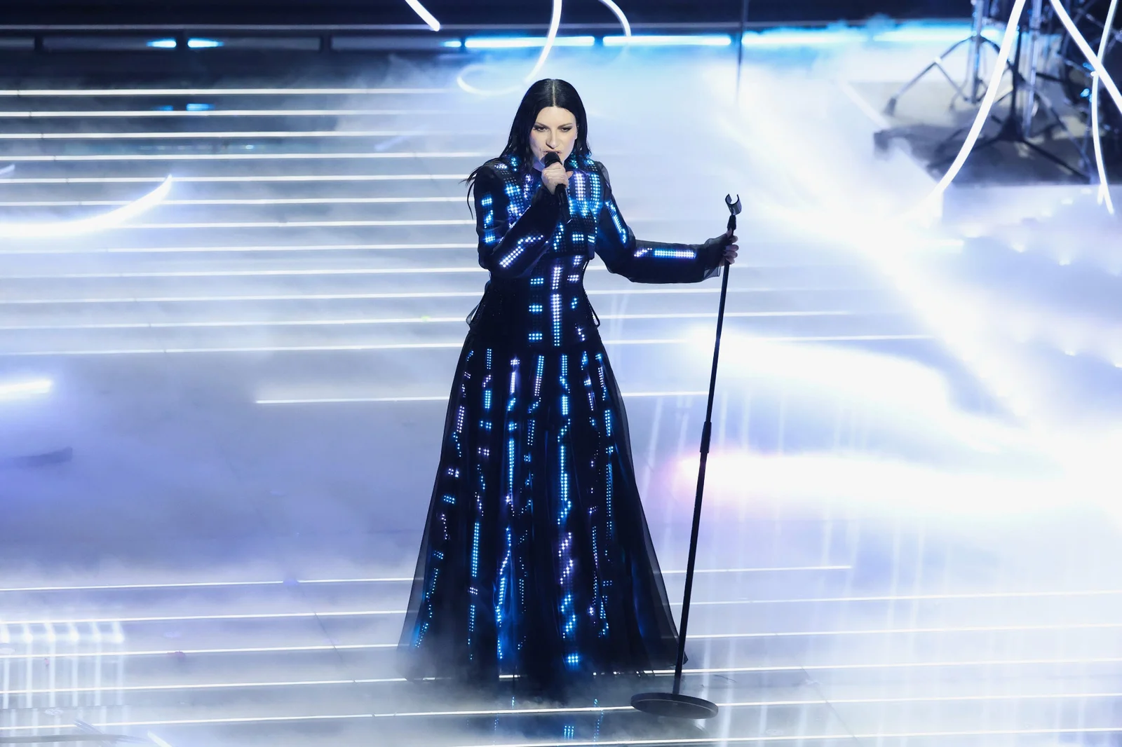 Laura Pausini performing at a microphone stand in illuminated CuteCircuit couture